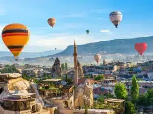 Hot air balloon floating over a mosque in Goreme at sunrise, showcasing Cappadocia's stunning landscape.