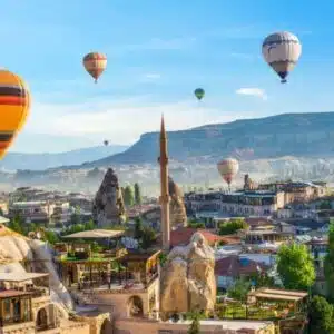 Hot air balloon floating over a mosque in Goreme at sunrise, showcasing Cappadocia's stunning landscape.