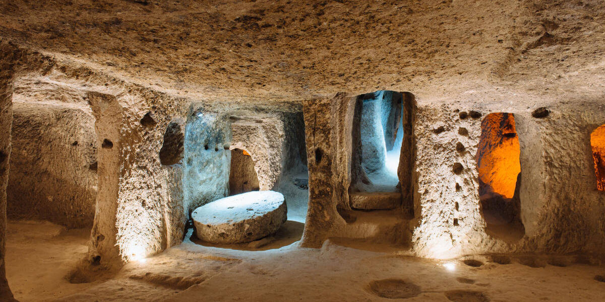 Illuminated stone corridors and chambers inside the ancient Derinkuyu underground city in Cappadocia, Turkey.
