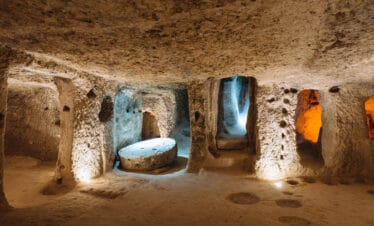 Illuminated stone corridors and chambers inside the ancient Derinkuyu underground city in Cappadocia, Turkey.