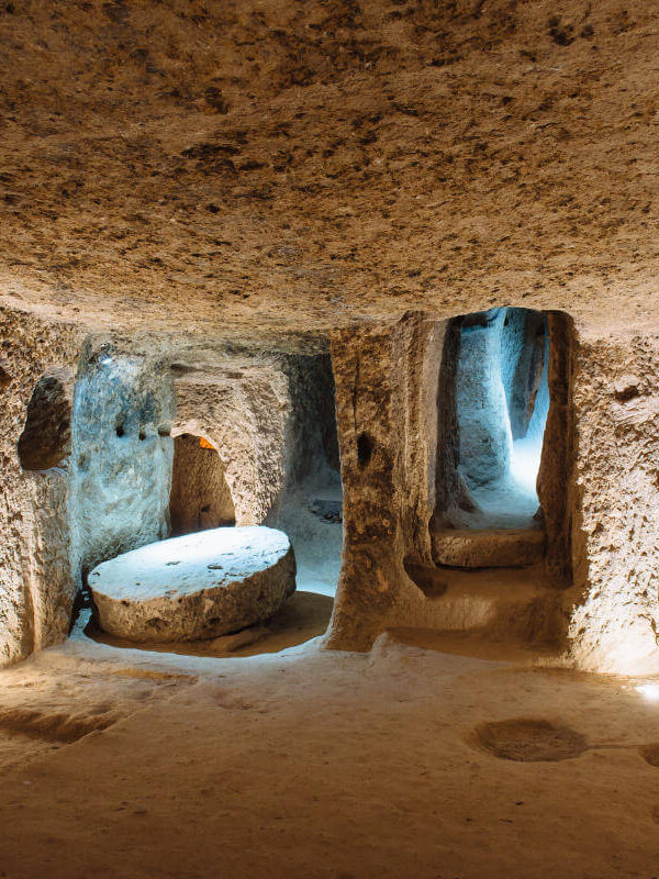 Illuminated stone corridors and chambers inside the ancient Derinkuyu underground city in Cappadocia, Turkey.