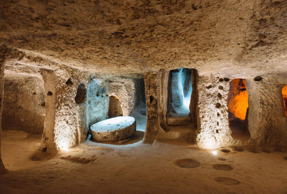 Illuminated stone corridors and chambers inside the ancient Derinkuyu underground city in Cappadocia, Turkey.