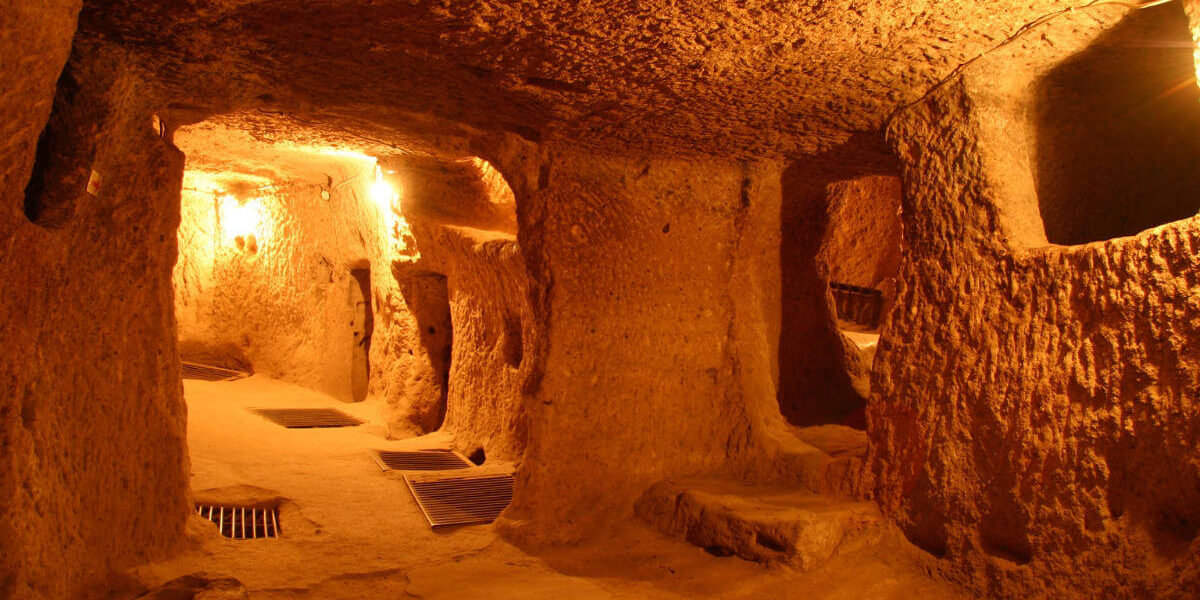 Narrow, dimly lit tunnels and chambers carved from rock in Kaymakli Underground City, Cappadocia, Turkey.