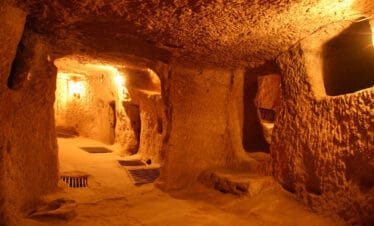 Narrow, dimly lit tunnels and chambers carved from rock in Kaymakli Underground City, Cappadocia, Turkey.