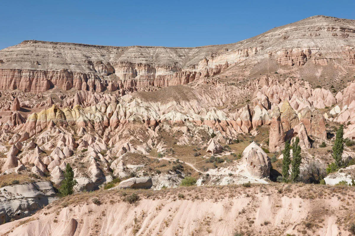 Eroded red rock formations in Cappadocia's Red Valley under soft daylight with rugged cliffs and unique terrain.