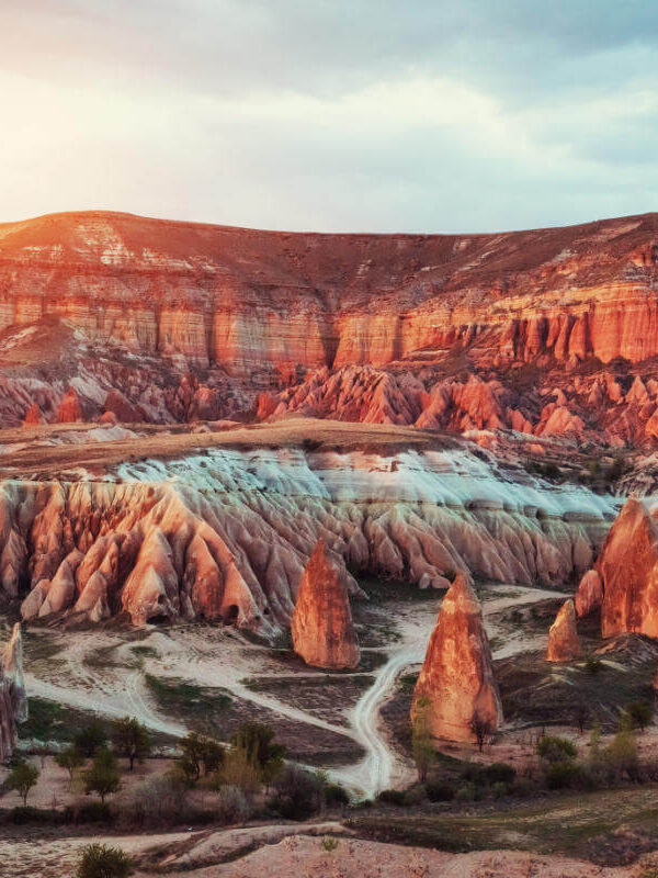 Vibrant sunset casting warm light over Red Valley's rugged rock formations in Cappadocia, Turkey.