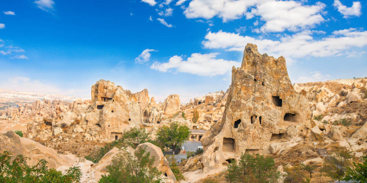 Ancient cave churches and rock-cut monasteries at Göreme Open-Air Museum in Cappadocia under a bright blue sky.