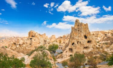Ancient cave churches and rock-cut monasteries at Göreme Open-Air Museum in Cappadocia under a bright blue sky.