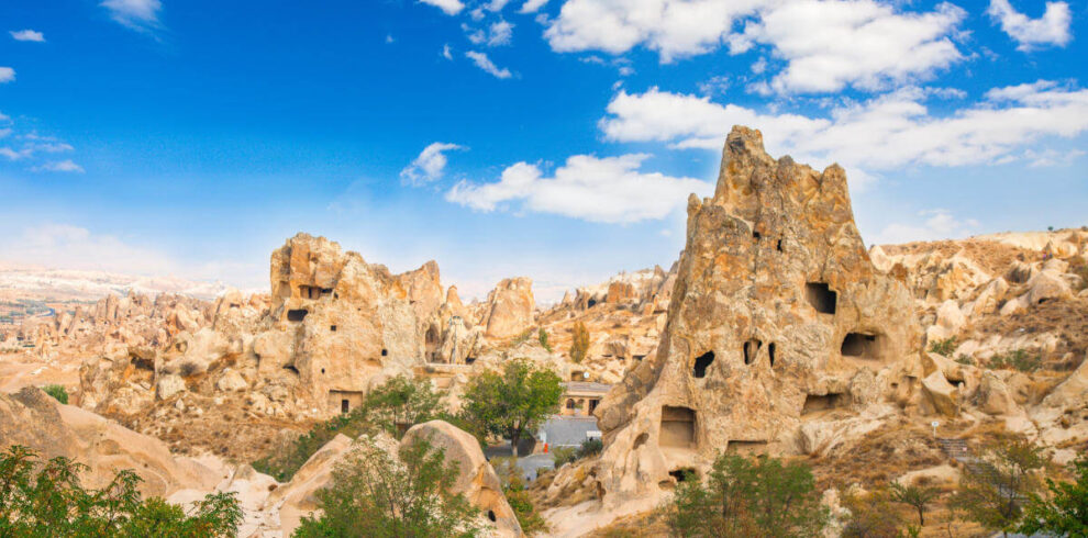 Ancient cave churches and rock-cut monasteries at Göreme Open-Air Museum in Cappadocia under a bright blue sky.