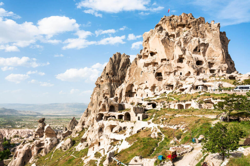 Uçhisar Castle with ancient cave homes carved into the rock, overlooking Cappadocia’s valleys under a clear sky.