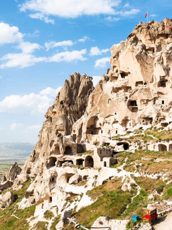Uçhisar Castle with ancient cave homes carved into the rock, overlooking Cappadocia’s valleys under a clear sky.