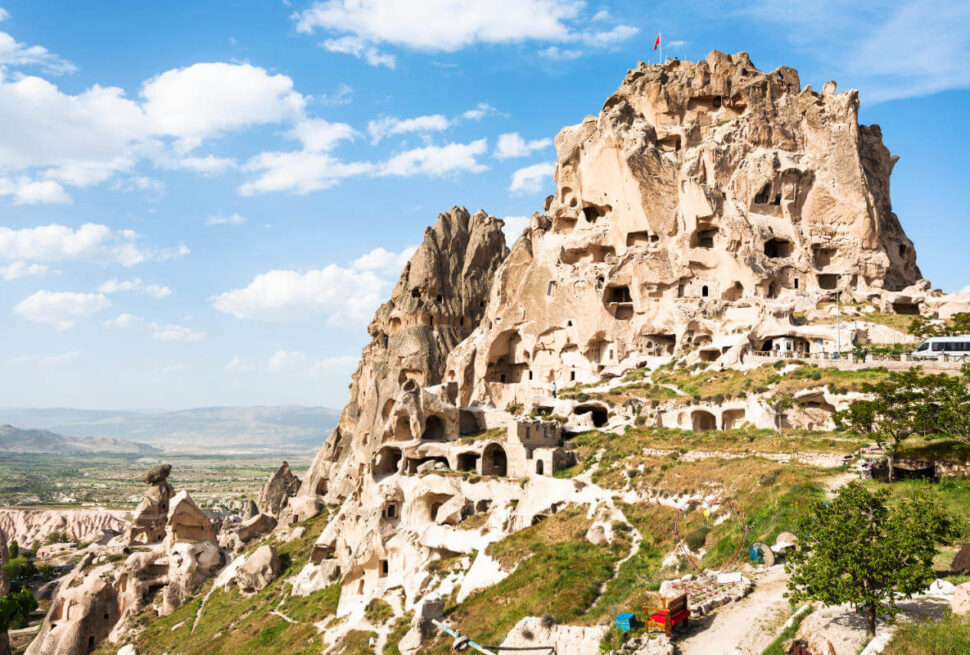 Uçhisar Castle with ancient cave homes carved into the rock, overlooking Cappadocia’s valleys under a clear sky.