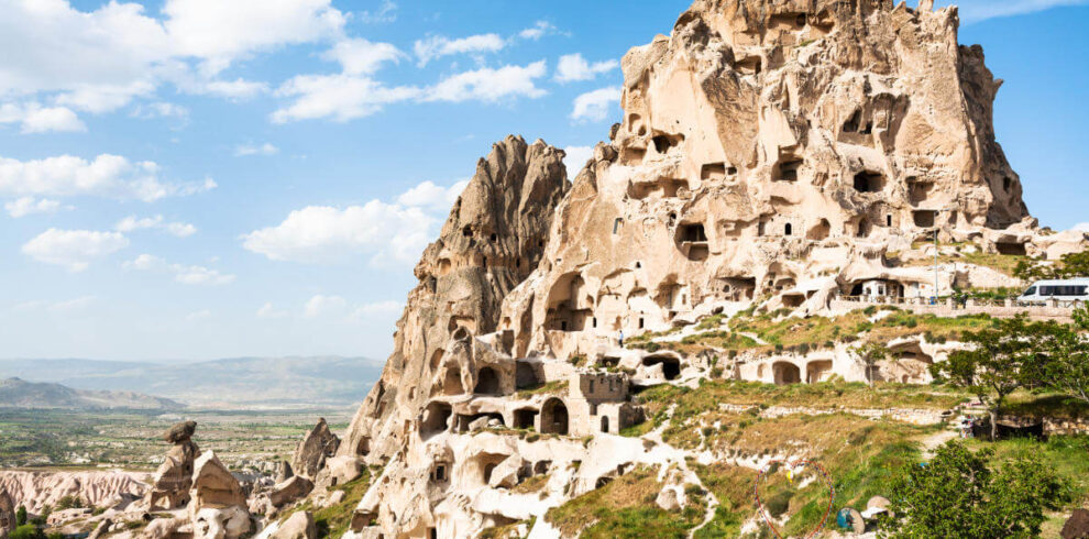 Uçhisar Castle with ancient cave homes carved into the rock, overlooking Cappadocia’s valleys under a clear sky.