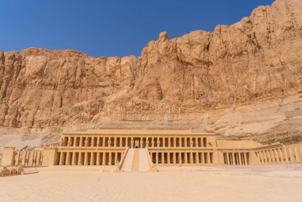 Mortuary Temple of Hatshepsut in Luxor, Egypt, built into towering cliffs with grand columns and symmetrical terraces.