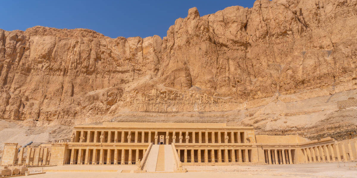 Mortuary Temple of Hatshepsut in Luxor, Egypt, built into towering cliffs with grand columns and symmetrical terraces.