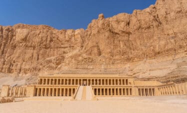 Mortuary Temple of Hatshepsut in Luxor, Egypt, built into towering cliffs with grand columns and symmetrical terraces.
