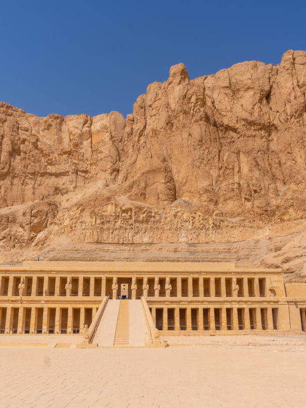 Mortuary Temple of Hatshepsut in Luxor, Egypt, built into towering cliffs with grand columns and symmetrical terraces.