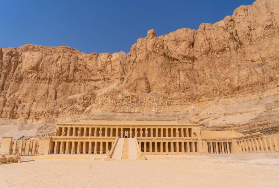 Mortuary Temple of Hatshepsut in Luxor, Egypt, built into towering cliffs with grand columns and symmetrical terraces.