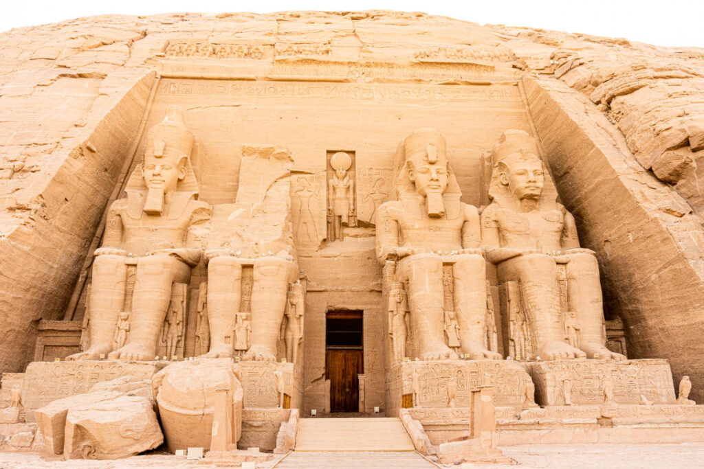 Abu Simbel Temple in Egypt featuring four colossal seated statues of Pharaoh Ramesses II carved into a sandstone cliff.