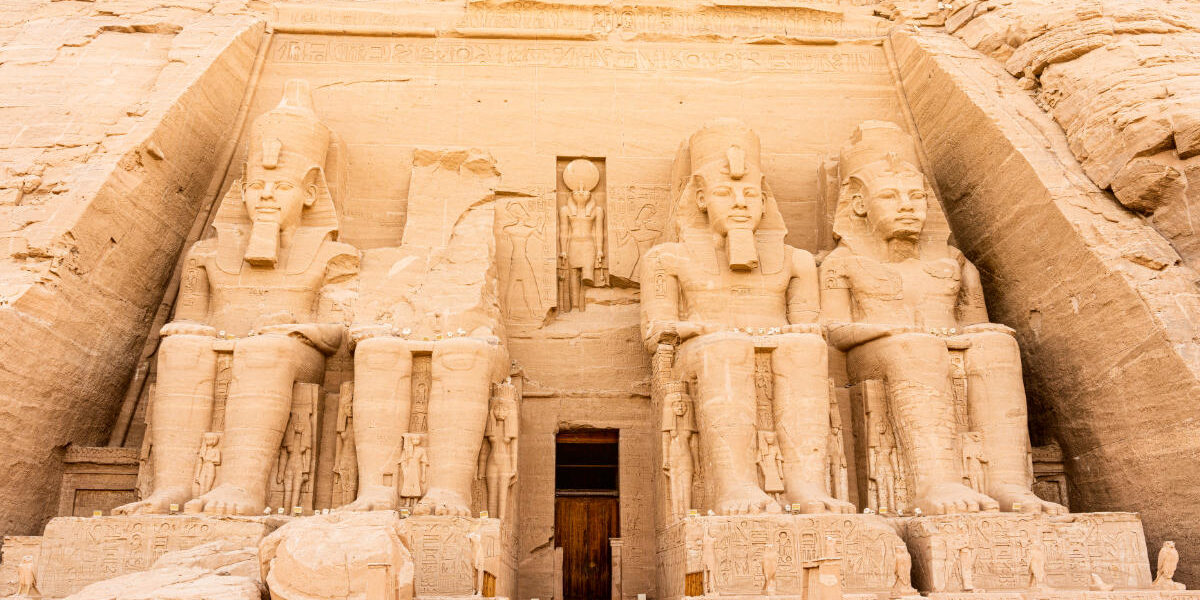 Abu Simbel Temple in Egypt featuring four colossal seated statues of Pharaoh Ramesses II carved into a sandstone cliff.