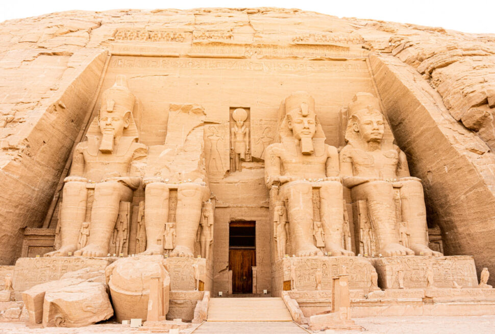 Abu Simbel Temple in Egypt featuring four colossal seated statues of Pharaoh Ramesses II carved into a sandstone cliff.