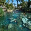 Tourists swimming in the ancient thermal waters of Cleopatra's Pool in Pamukkale, Turkey, surrounded by ruins.