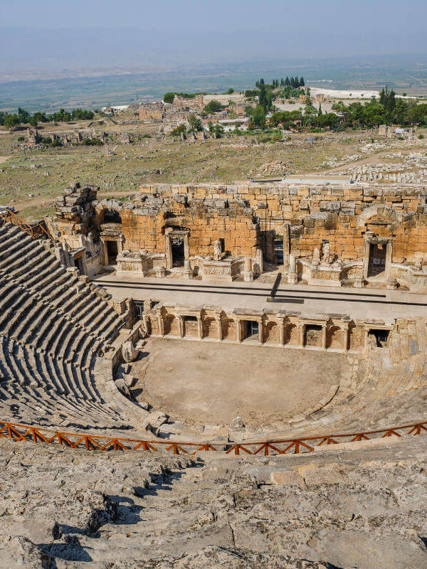Panoramic view of the Ancient Theatre of Hierapolis in Pamukkale, Turkey, with stone seating and preserved Roman stage.