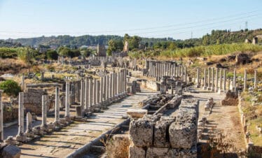 Ruins of the ancient agora in Perge, Antalya, Turkey, featuring stone columns and walkways from the Roman period.