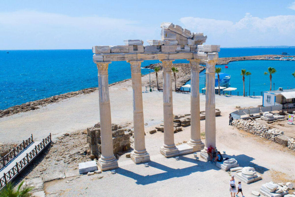 Ruins of the Temple of Apollo in Side, Antalya, Turkey, with standing marble columns near the blue Mediterranean coast.
