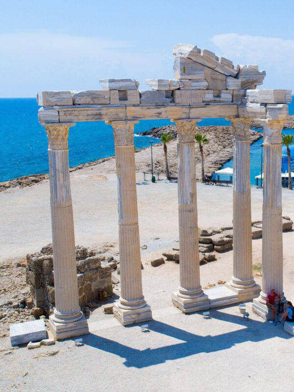 Ruins of the Temple of Apollo in Side, Antalya, Turkey, with standing marble columns near the blue Mediterranean coast.
