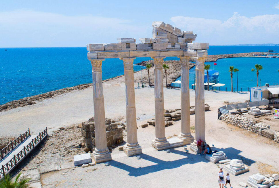 Ruins of the Temple of Apollo in Side, Antalya, Turkey, with standing marble columns near the blue Mediterranean coast.