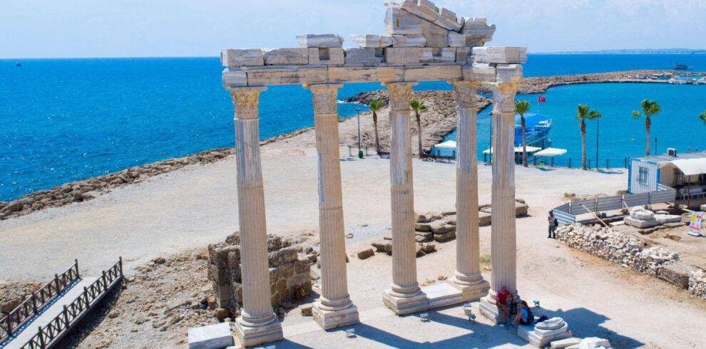 Ruins of the Temple of Apollo in Side, Antalya, Turkey, with standing marble columns near the blue Mediterranean coast.