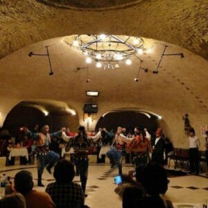 Traditional folk dancers perform at a Cappadocia Turkish Night Show in a cave restaurant venue with a seated audience