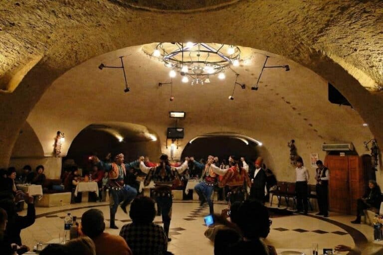 Traditional folk dancers perform at a Cappadocia Turkish Night Show in a cave restaurant venue with a seated audience