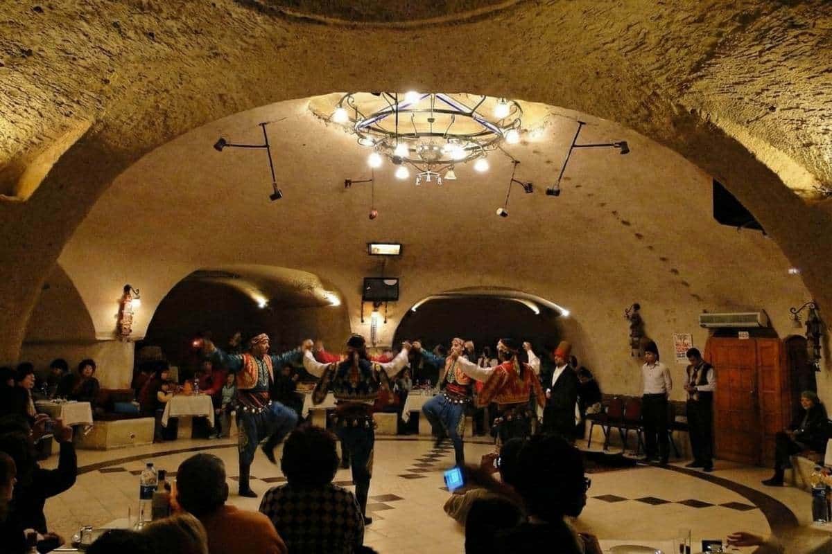 Traditional folk dancers perform at a Cappadocia Turkish Night Show in a cave restaurant venue with a seated audience