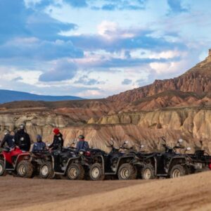 Group of travelers on ATVs exploring Cappadocia’s rocky valleys under a vibrant evening sky.