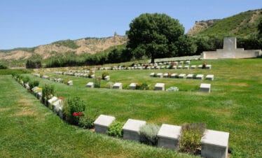 View of Beach Cemetery at Gallipoli Peninsula in Çanakkale, Turkey, with aligned gravestones and sea in the background.