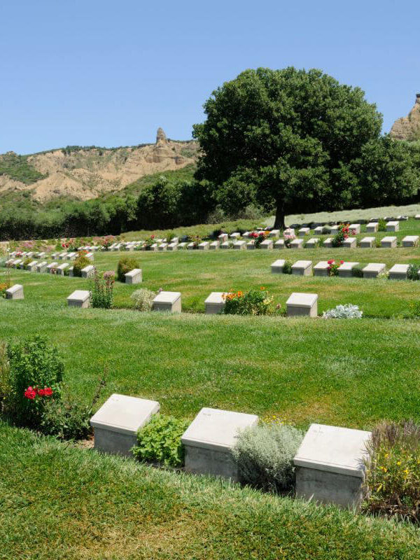 View of Beach Cemetery at Gallipoli Peninsula in Çanakkale, Turkey, with aligned gravestones and sea in the background.