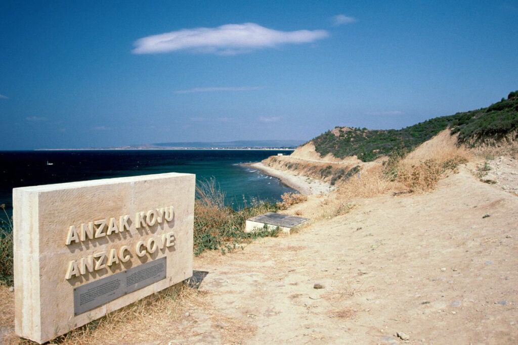 ANZAC Cove memorial stone overlooking the historic Gallipoli coastline in Çanakkale, Turkey under a clear blue sky.
