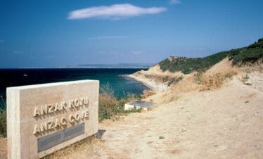 ANZAC Cove memorial stone overlooking the historic Gallipoli coastline in Çanakkale, Turkey under a clear blue sky.