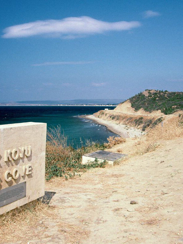 ANZAC Cove memorial stone overlooking the historic Gallipoli coastline in Çanakkale, Turkey under a clear blue sky.
