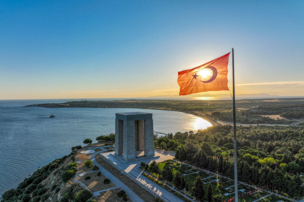 Çanakkale Martyrs' Memorial with Turkish flag waving at sunset in Gallipoli Peninsula, Çanakkale, Turkey.