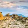 Ruins of the Byzantine Gate in Hierapolis, Turkey, with stone columns and distant mountains under a colorful evening sky.