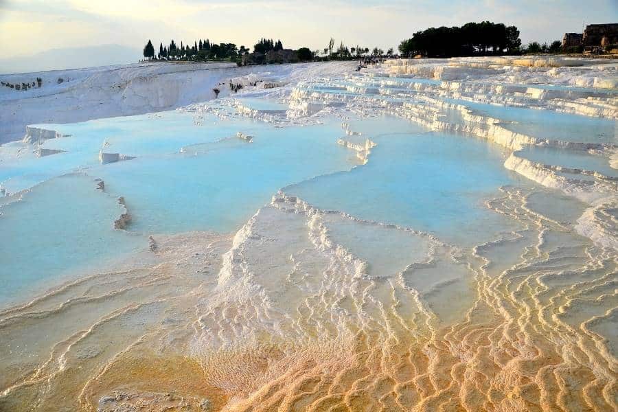 A stunning view of Pamukkale’s white limestone terraces with clear blue water pools cascading down the hillside.