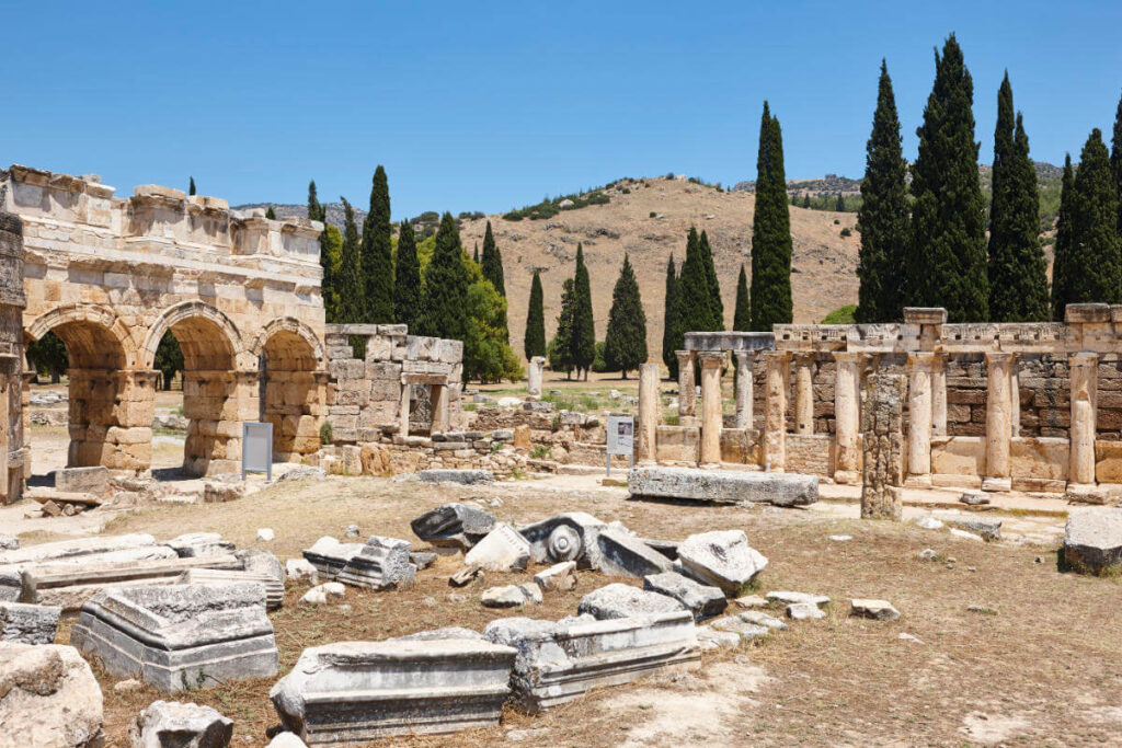 Stone ruins and Roman arches of Hierapolis ancient city under blue sky in Pamukkale, Turkey.