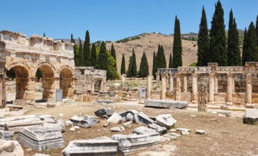 Stone ruins and Roman arches of Hierapolis ancient city under blue sky in Pamukkale, Turkey.