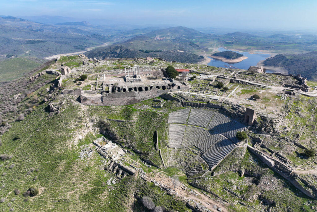 Steeply tiered Pergamon Ancient Theater built into a hillside in Turkey, overlooking lush valley and ruins below.