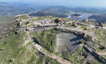 Steeply tiered Pergamon Ancient Theater built into a hillside in Turkey, overlooking lush valley and ruins below.