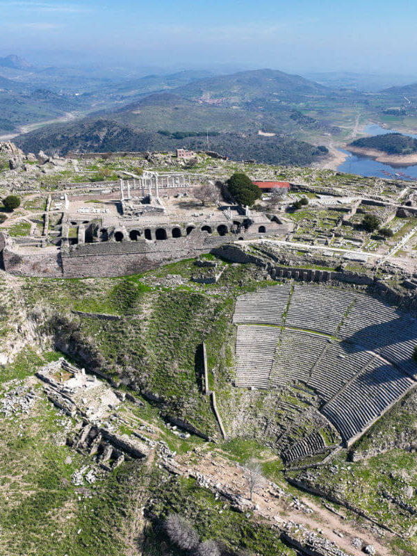 Steeply tiered Pergamon Ancient Theater built into a hillside in Turkey, overlooking lush valley and ruins below.