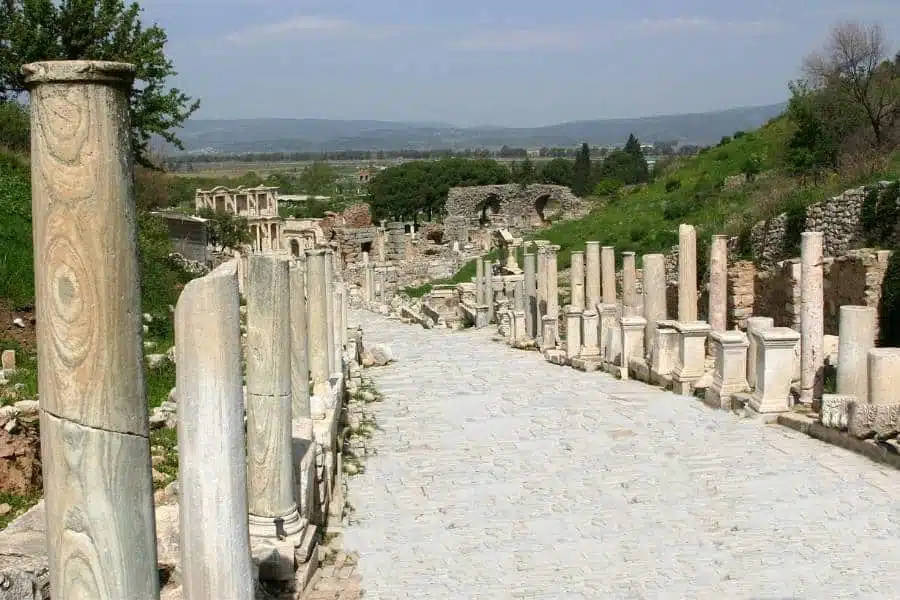 Stone-paved Curetes Street in Ephesus, flanked by ancient marble columns, leading through the historic ruins of the ancient city.